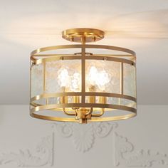 a light fixture in a room with white wallpaper and gold trimmings on the ceiling