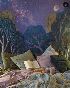 a bed with pillows and blankets on it in front of a wall painted with trees