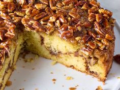 a cake with pecans on top and one slice missing from it, sitting on a white plate