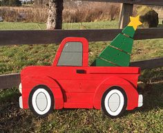 a wooden toy truck with a christmas tree on the back in front of a fence