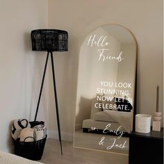 a room with a mirror, lamp and basket on the floor in front of it that says hello friends you look stunning now let's celebrate