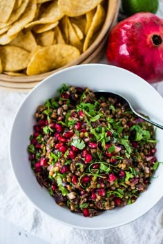 a white bowl filled with food next to an apple and some tortilla chips