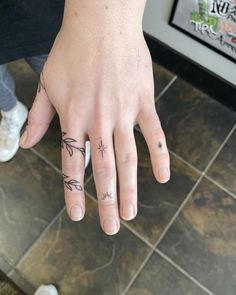 a person's hand with two small tattoos on it, and the other half of their fingers