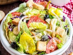 a salad in a white bowl with croutons on the side