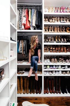 a woman sitting on top of a white shelf in a closet filled with lots of shoes