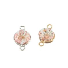 two charms with pink and white flowers on the front, one has a gold plated clasp