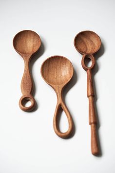 three wooden spoons and a ladle on a white surface