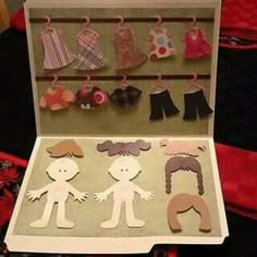 an open cardboard box with paper cutouts of children's clothing and clothes pins