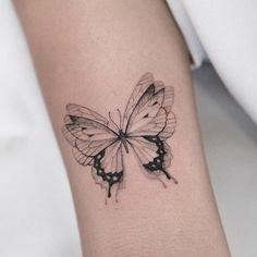 a black and white butterfly tattoo on the wrist