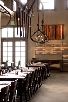 an empty restaurant with tables and chairs in front of large windows that have lights hanging from them