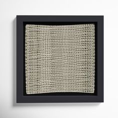 a black frame with a white cloth on the wall in front of it is an image of woven fabric