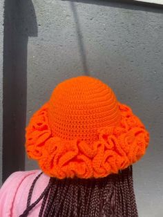 an orange crocheted hat is on top of a woman's head