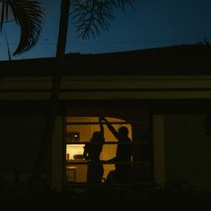 two people standing in front of a window at night with their arms around each other