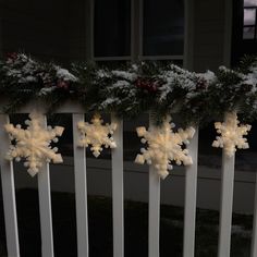 three snowflakes are hanging on the railings in front of a house decorated for christmas