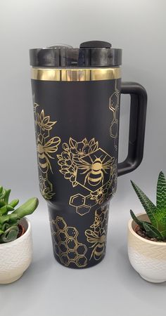 a black and gold coffee cup next to some succulents