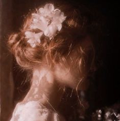 a woman with flowers in her hair looking out the window at something on the ground