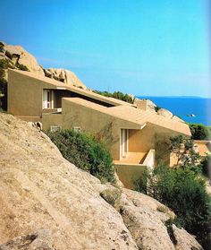 a house sitting on top of a rocky hillside next to the ocean