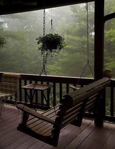 a wooden porch swing with a plant hanging from it's back end on a foggy day