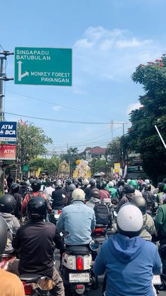 a group of people riding motorcycles down a street next to a traffic light and sign