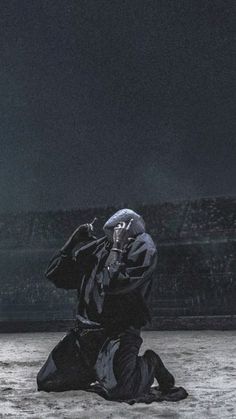 a man sitting on the ground in front of a stadium