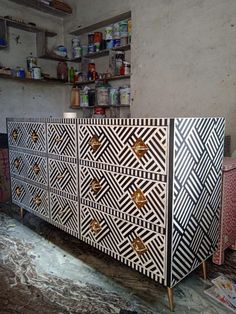 a cabinet that has been decorated with black and white designs on the front, gold knobs at the top