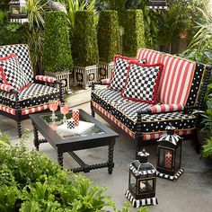 a living room filled with lots of furniture covered in red and black checkered cushions