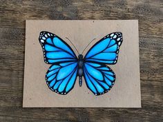 a blue butterfly sitting on top of a piece of paper