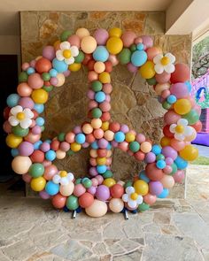 the letter o made out of balloons is displayed in front of a stone wall