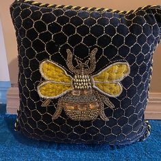 a blue cushion with a yellow bee on it's front and back sides, sitting on a blue carpet