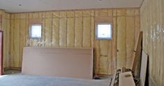 an unfinished room with two windows in the wall and insulation on the walls behind it