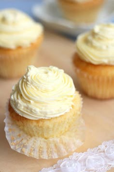 three cupcakes with white frosting sitting on a table