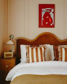 a bed with two pillows on top of it next to a night stand and lamp