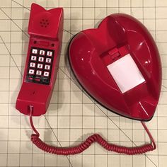 an old red phone is next to a heart shaped object