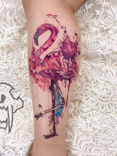 a flamingo tattoo on the leg with watercolor paint splattered over it