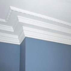 the corner of a room with blue walls and white crown moldings on the ceiling