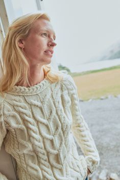 a woman in a white sweater looking out the window