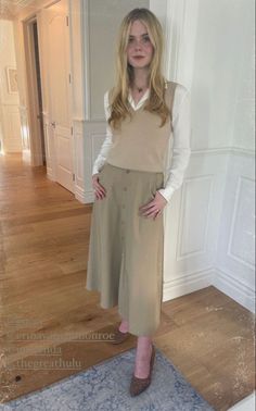 a woman standing in front of a door wearing a tan skirt and beige sweater vest