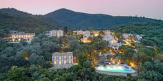 an aerial view of a mansion surrounded by trees and mountains at night with pool in foreground