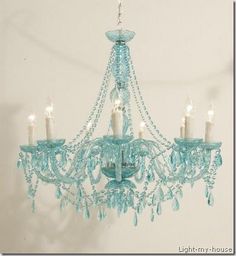 a blue chandelier hanging from the ceiling with candles in front of it,