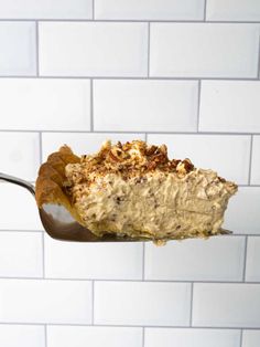 a piece of cake on a spoon in front of a white brick wall