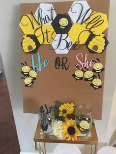 a sign that says he or she with bees and sunflowers on it in front of a table