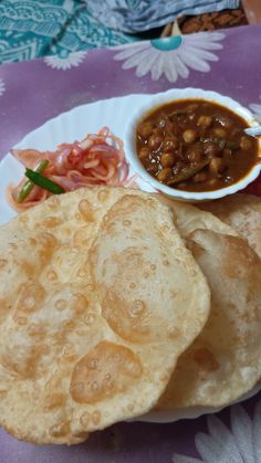 a white plate topped with tortillas and beans next to a bowl of chili