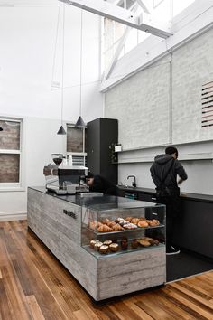 a man standing in front of a counter filled with pastries and doughnuts