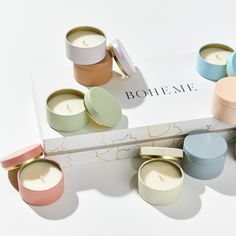 several different colored candles sitting next to each other on a white surface with the word boiteme written in it