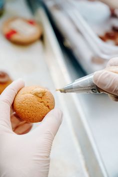 a person in white gloves is holding a cookie and writing something on it with a pen