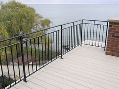 a balcony overlooking the ocean with black iron railings and wood flooring, along with a brick fire hydrant