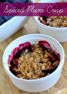 two bowls filled with fruit and granola on top of a wooden table next to blueberries