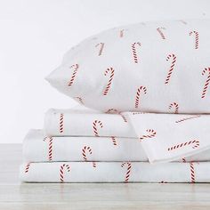 three white sheets with candy canes on them are stacked up next to each other