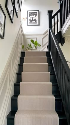 there is a black and white staircase with pictures on the wall