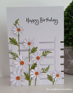 a birthday card with daisies on it and a potted plant in the background